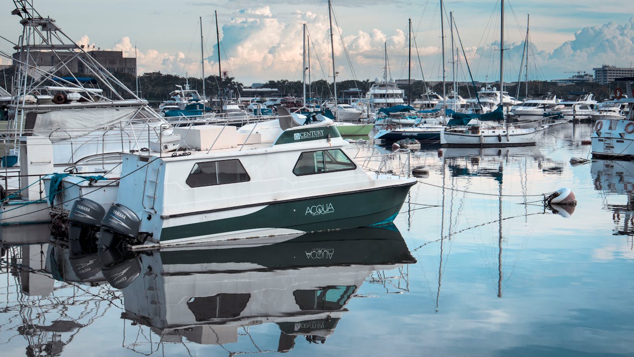 about-us-02 Tranquil marina with docked boats reflecting on calm water.